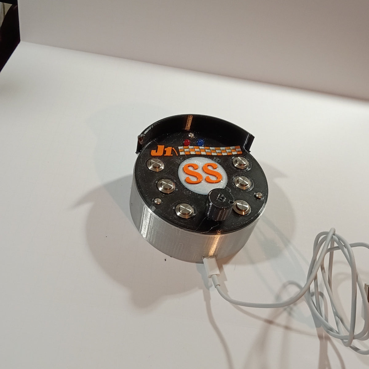 J1 SS black round USB button box photographed on a white backdrop