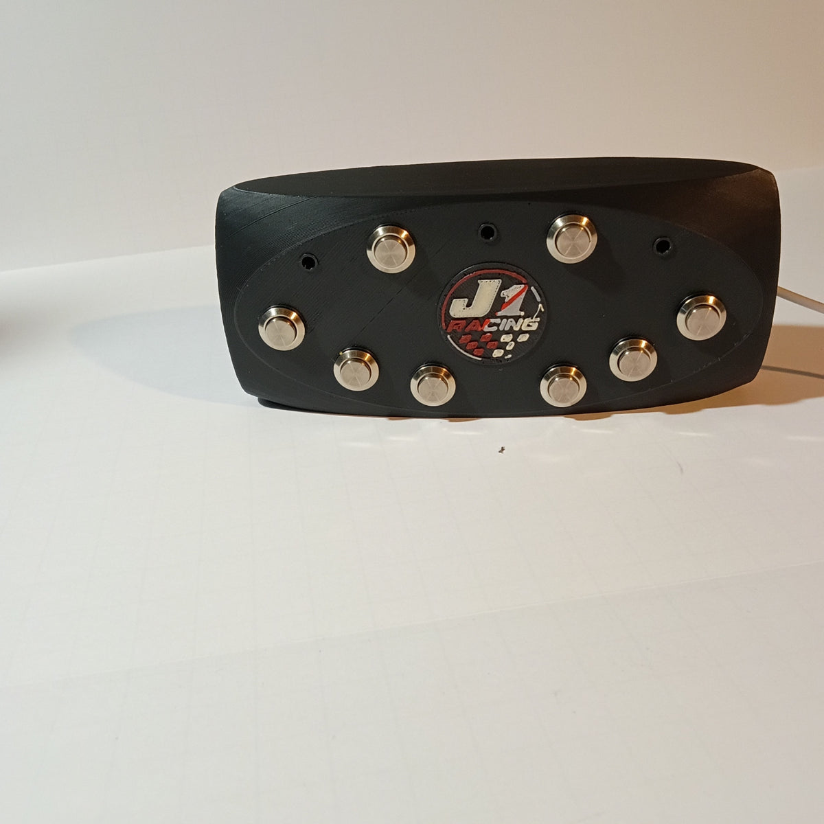 J1 black oval button box with eight silver metal buttons and center J1 badge